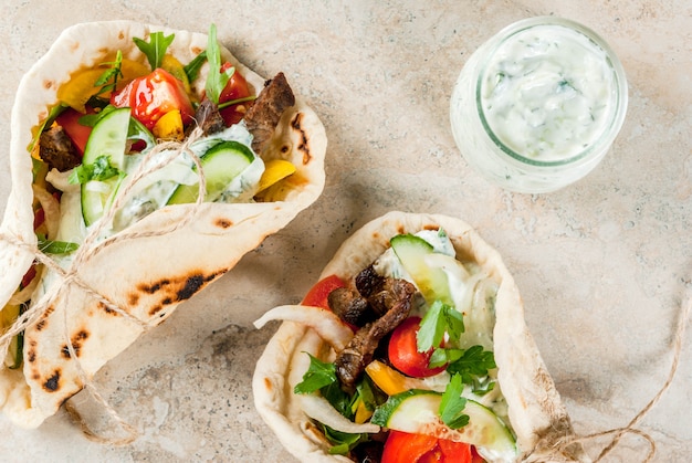 Spuntino salutare, pranzo. Gyros sandwich tradizionali greci avvolti - tortillas, pita di pane con ripieno di verdure, carne di manzo e salsa tzatziki