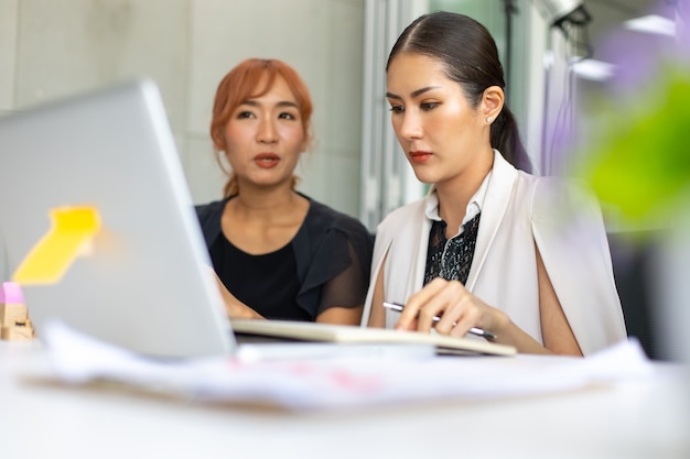 Squadra asiatica della donna di affari che lavora al computer portatile nella sala riunioni. Gente di affari professionale di brainstorming e concetto di lavoro di squadra.