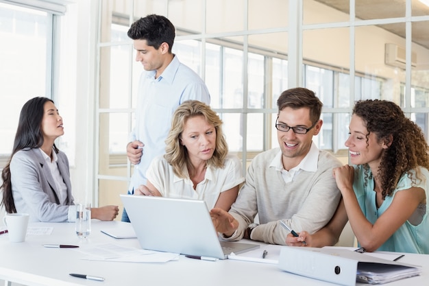 Squadra casuale di affari che ha una riunione facendo uso del computer portatile