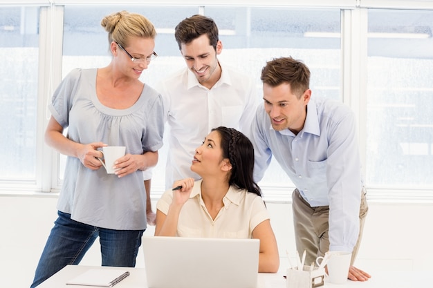 Squadra casuale di affari che ha una riunione facendo uso del computer portatile