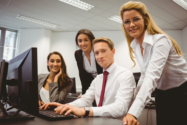 Squadra casuale di affari che lavora insieme allo scrittorio facendo uso del computer portatile