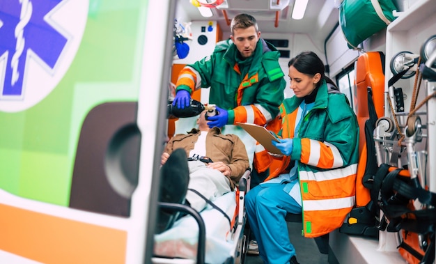 Squadra del servizio medico di emergenza con paziente anziano in un'ambulanza