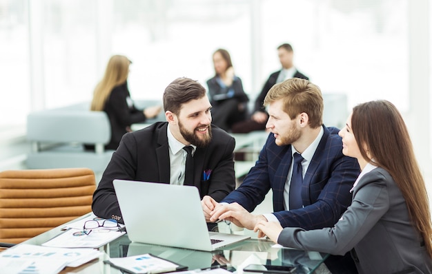 squadra di affari che lavora al laptop e che fa il rapporto finanziario corrente seduto alla tua scrivania in ufficio.