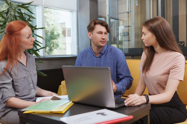 Squadra di affari che utilizza un computer portatile durante la riunione presso l'area di lavoro moderna