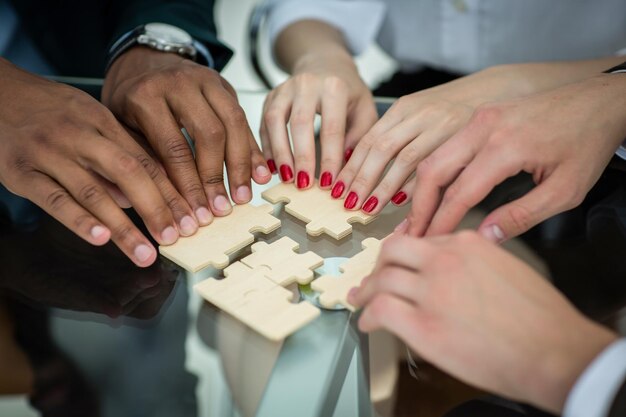 Squadra di affari del primo piano con i pezzi di un puzzle dietro una scrivania