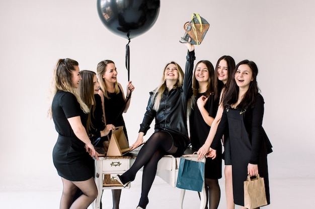 Squadra di affari di donne attraenti sexy che celebrano il compleanno del collega femminile in studio. Incontro di amici, festa di compleanno di una bella ragazza, che ha ricevuto una borsa alla moda come regalo.