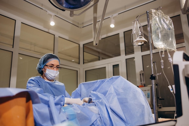 Squadra di medici o chirurghi con monitor dell'elettrocardiogramma in chirurgia ospedaliera che opera nel pronto soccorso che mostra il concetto medico della frequenza cardiaca del paziente