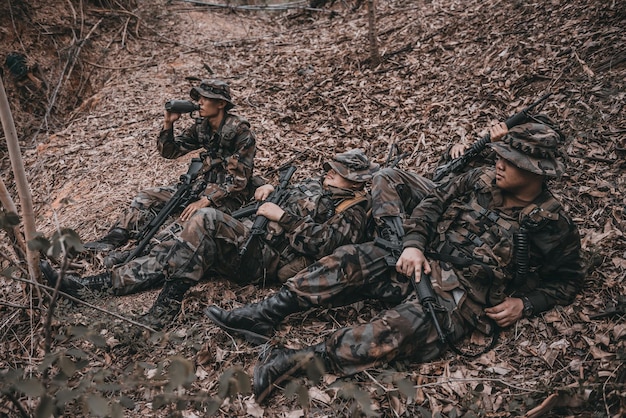 Squadra di soldato dell'esercito con la mitragliatrice che si muove nella forestaSoldato della milizia thailandese in uniforme da combattimento nel boscoViaggiare la pattuglia in pendenza nella foresta pluviale