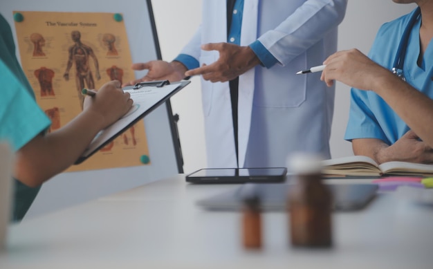 Squadra medica che ha un incontro con i medici in camice bianco e scrub chirurgico seduti a un tavolo che discutono di un record di pazientiassistenza sanitaria medica di successo Concetto di lavoro del medico di medicina