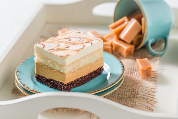 Squisita torta al caramello su porcellana blu con barrette di cioccolato fondente