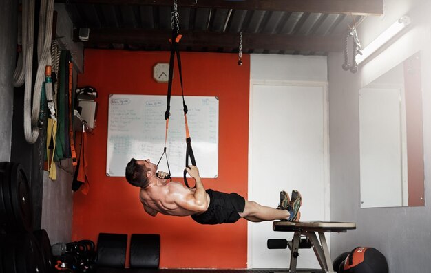 Sta arrivando in cima Foto a figura intera di un giovane uomo bello e muscoloso che si allena in palestra