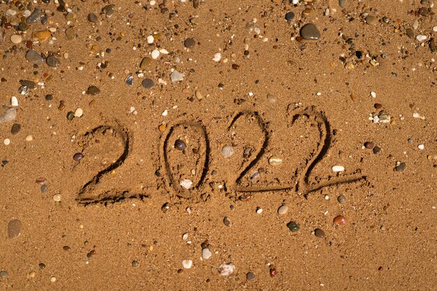 sta disegnando sulla sabbia su una spiaggia con un'onda in riva al mare vacanza al mare concetto di capodanno