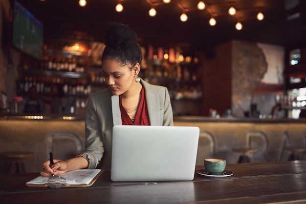 Sta facendo molto Ritagliata foto di una giovane donna d'affari che lavora al suo laptop in un caffè