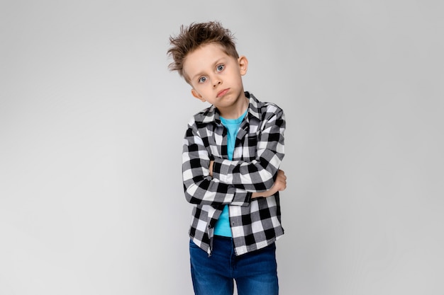 Sta un bel ragazzo in camicia a quadri, camicia blu e jeans