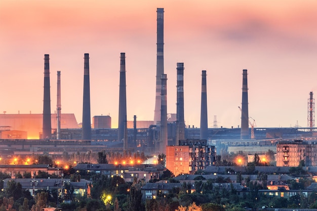 Stabilimento siderurgico al tramonto a Mariupol Ucraina prima della guerra Fabbrica siderurgica con ciminiere Acciaierie opere in ferro Industria pesante Paesaggio industriale con mietitrebbia metallurgica fuma luci