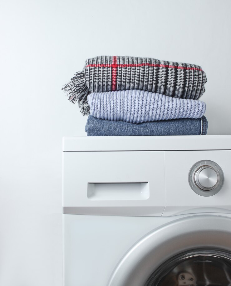 Stack of clothes on washing machine against a white surface