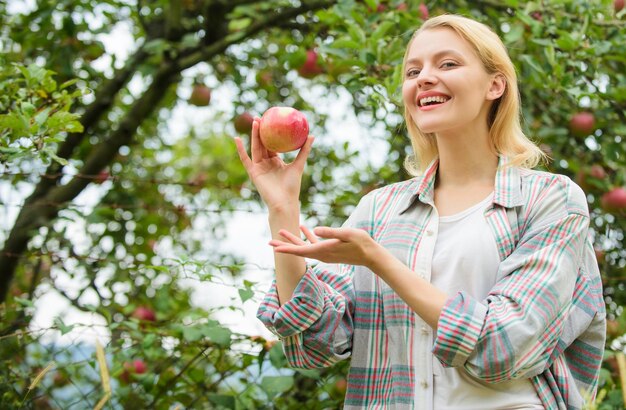 Stagione autunnale nel frutteto giardiniere del frutteto ragazza nel giardino delle mele denti sani fame vitamina e dieta alimentare Donna felice che mangia mela raccolto primaverile frutta estiva donna con mela nel frutteto