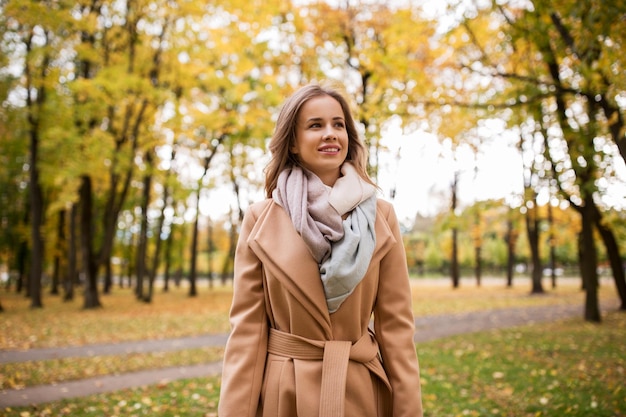 stagione e concetto di persone - bella giovane donna felice che cammina nel parco autunnale