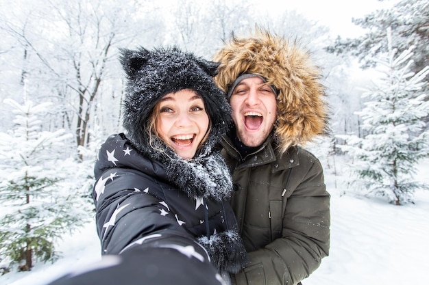 Stagione e concetto di relazione coppia divertente che si fa selfie in inverno