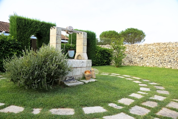 Stagione estiva in Italia. Progettazione di pozzo d'acqua in un elegante giardino.