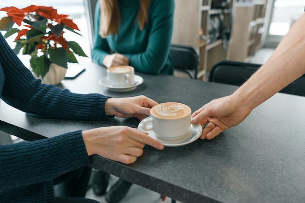 Stagione invernale nella caffetteria. Mano del primo piano del barista dell&#39;uomo con la tazza di caffè di arte