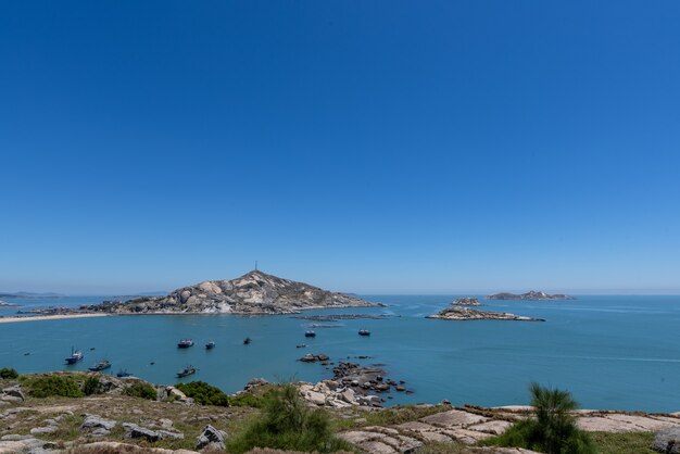 Stai in alto e guarda lo scenario del mare sotto il cielo blu, l'acqua blu, le onde bianche e le rocce nere