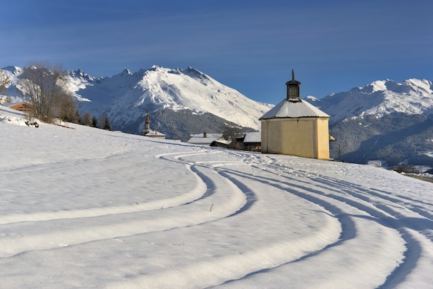 Stampa di sci di fondo andando ad una piccola cappella in un bellissimo paesaggio montano innevato