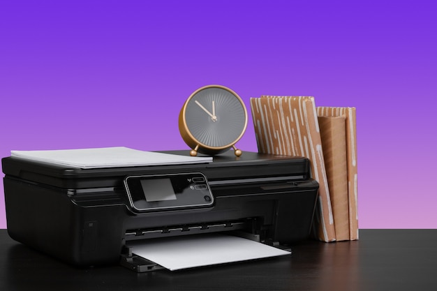 Stampante laser domestica sulla scrivania su sfondo viola