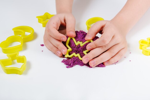 Stampi in plastica per sabbia cinetica viola per sabbia. Il bambino scolpisce e gioca con la sabbia. Vista in primo piano