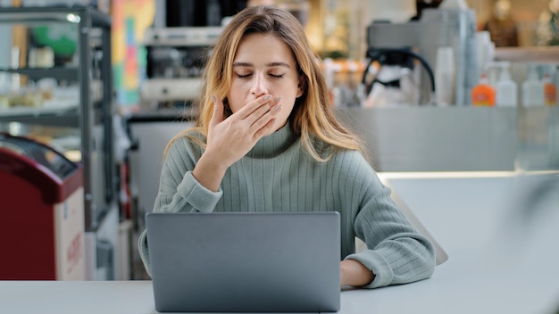 Stanca esausta donna d'affari studentessa chiude il laptop che smette di funzionare sente il bisogno di sbadigli stanchi