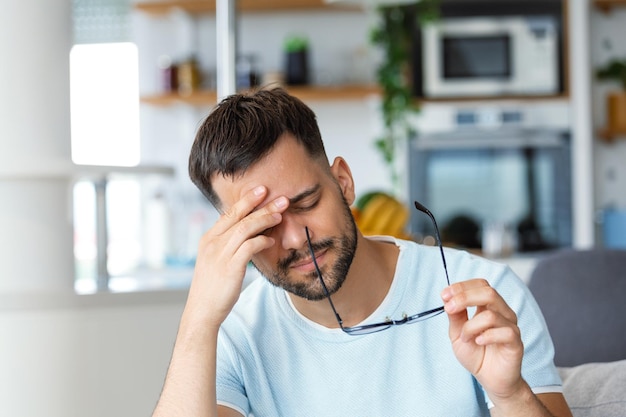 Stanco maschio da togliere gli occhiali massaggiare gli occhi si sente affaticato soffre di forte mal di testa esausto uomo malato che ha affaticamento degli occhi o astigmatismo sopraffatto dal lavoro Concetto di problema di salute