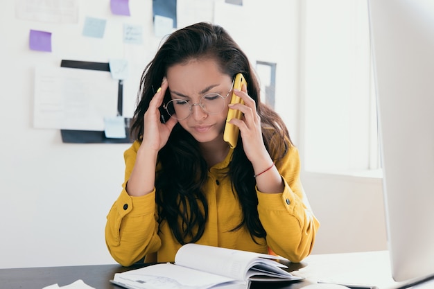 Stanco sconvolto giovane donna freelance o impiegato che parla dal suo telefono