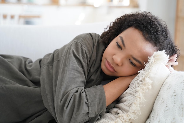 Stanco sconvolto ragazza adolescente afroamericana sdraiata sul divano a casa da sola Problemi adolescenziali affaticamento