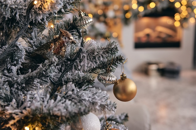 Stanza accogliente decorata, albero di Natale in neve d'argento con giocattoli a bolle d'oro, luci e regali sotto di esso. Bella decorazione per la casa fatta a mano fai da te. L'interno di Capodanno in uno studio fotografico.