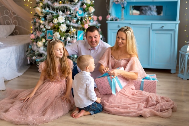 Stanza di Natale con la famiglia felice che si siede vicino all'albero di Natale