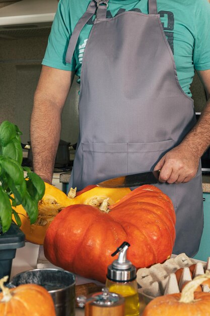 Stare a casa e cucinare. Ravioli di ricotta di zucca fatti in casa. Mani dell'uomo per tagliare la zucca.