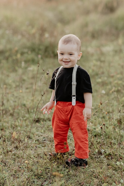 Stare sorridente del piccolo neonato sveglio sull'erba nel campo di estate