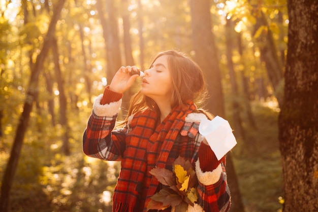 Starnuti ragazza con tergicristallo naso tra alberi gialli nel parco donna fa una cura per il col comune...