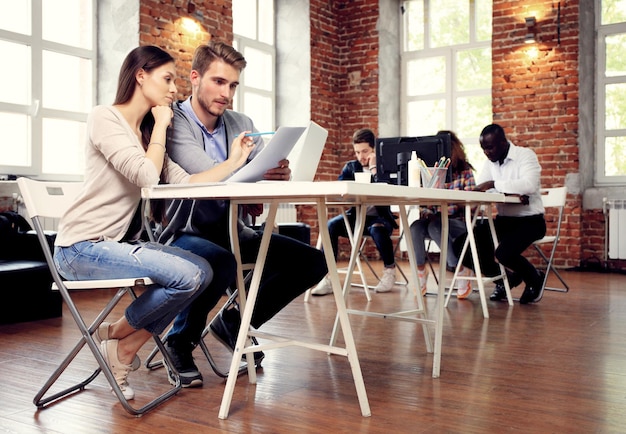 Startup Diversità Lavoro di squadra Brainstorming Concetto di riunione Colleghi del team aziendale Condivisione dell'economia mondiale Rapporto Documento portatilePersone che lavorano Pianificazione Start UpGruppo giovani hipster che discutono di caffè