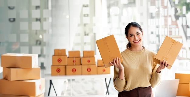 Startup PMI piccola impresa imprenditore con scatola di carta in piedi nel suo ufficio a casa Bella donna d'affari di successo marketing online che prepara la consegna del pacco al suo cliente