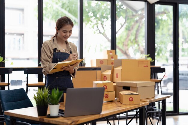 Startup PMI piccola impresa imprenditore PMI o donna asiatica freelance che utilizza un laptop con scatola di imballaggio di marketing online e concetto di PMI di consegna