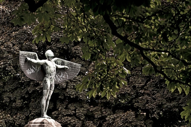 Statua alata contro alberi lussureggianti