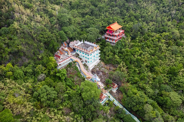 Statua del drago con il tempio e santuario rosso sulla collina nella foresta pluviale tropicale a Wat Ban Tham