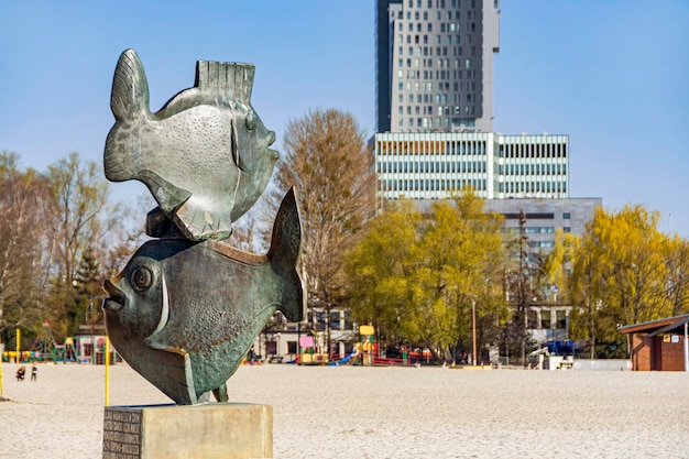 Statua della scultura dei pesci con la spiaggia a Gdynia