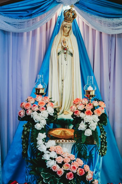 Statua della Vergine Maria e la corona sullo sfondo di una tenda blu