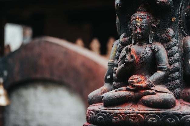 Statua idolo del Buddha nero con polvere di colore rosso arancione giallo in Durbar Square, Nepal