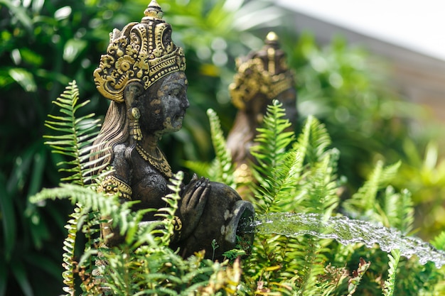 Statuetta balinese di una ragazza con una pentola da cui scorre l'acqua. Decorazione della piscina.