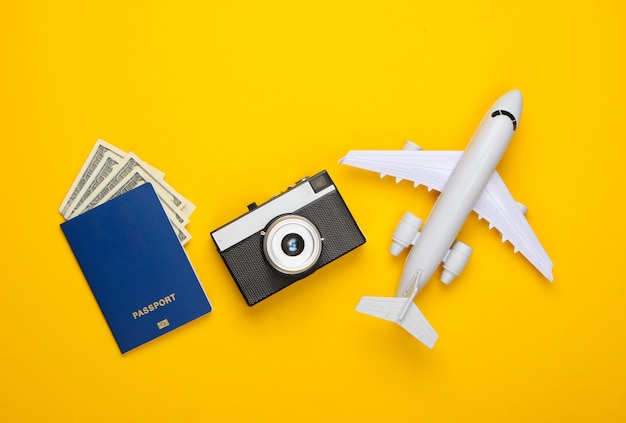 Statuetta di aereo, macchina fotografica, passaporto su un giallo.