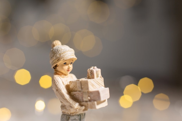 Statuette decorative a tema natalizio, statuetta di una ragazza con scatole con regali per Natale nelle sue mani,