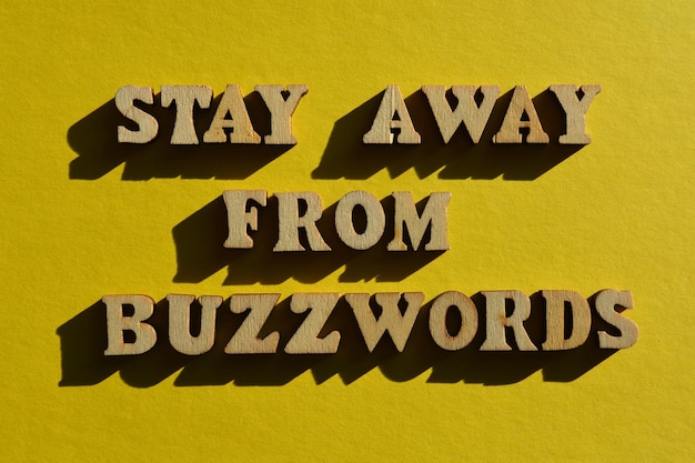 Stay Away From Buzzwords parole in lettere di alfabeto in legno isolate su uno sfondo giallo brillante